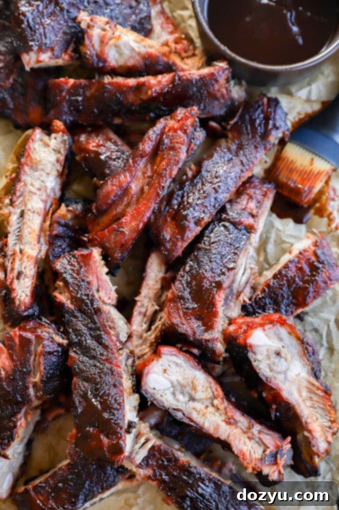 Fall-Off-The-Bone Apple Cider Traeger Ribs 2 tray of bbq traeger pork ribs with BBQ sauce in bowl