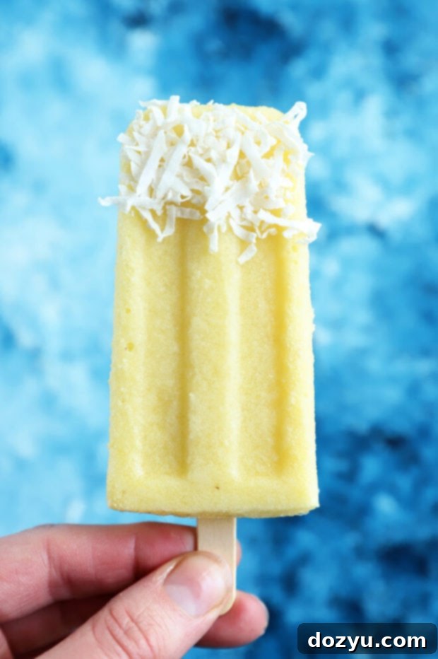 Tropical Pina Colada Popsicles 2 Hand holding pina colada popsicle, highlighting the creamy texture and tropical appeal