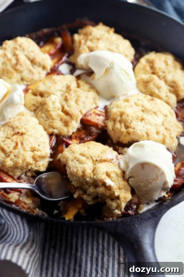Flame-Kissed Peach Cobbler 3 Spooning out biscuit from skillet image