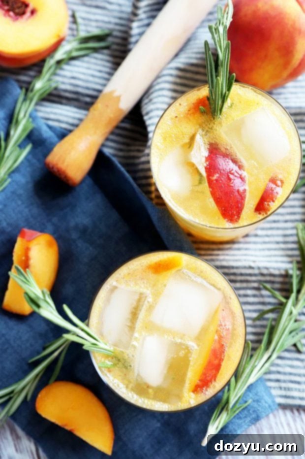 Overhead image of a Sparkling Rosemary Peach Mocktail garnished with rosemary and peach slices, sitting on a rustic surface.