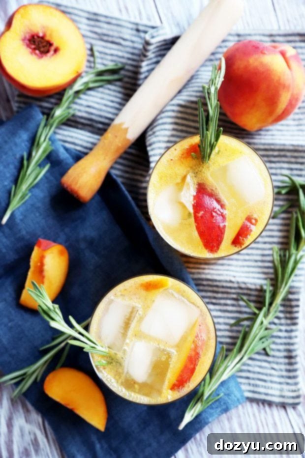 Overhead photo of two sparkling rosemary peach mocktails, with fresh rosemary sprigs and peach slices on the side.
