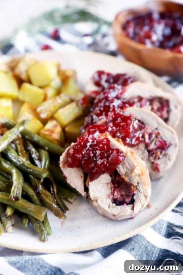 Festive Sheet Pan Stuffed Pork Tenderloin 5 Side photo of slices of stuffed pork on a plate