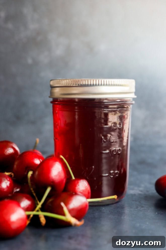 Sweet Cherry Elixir 2 flavored syrup in a jar with fresh cherries in a pile