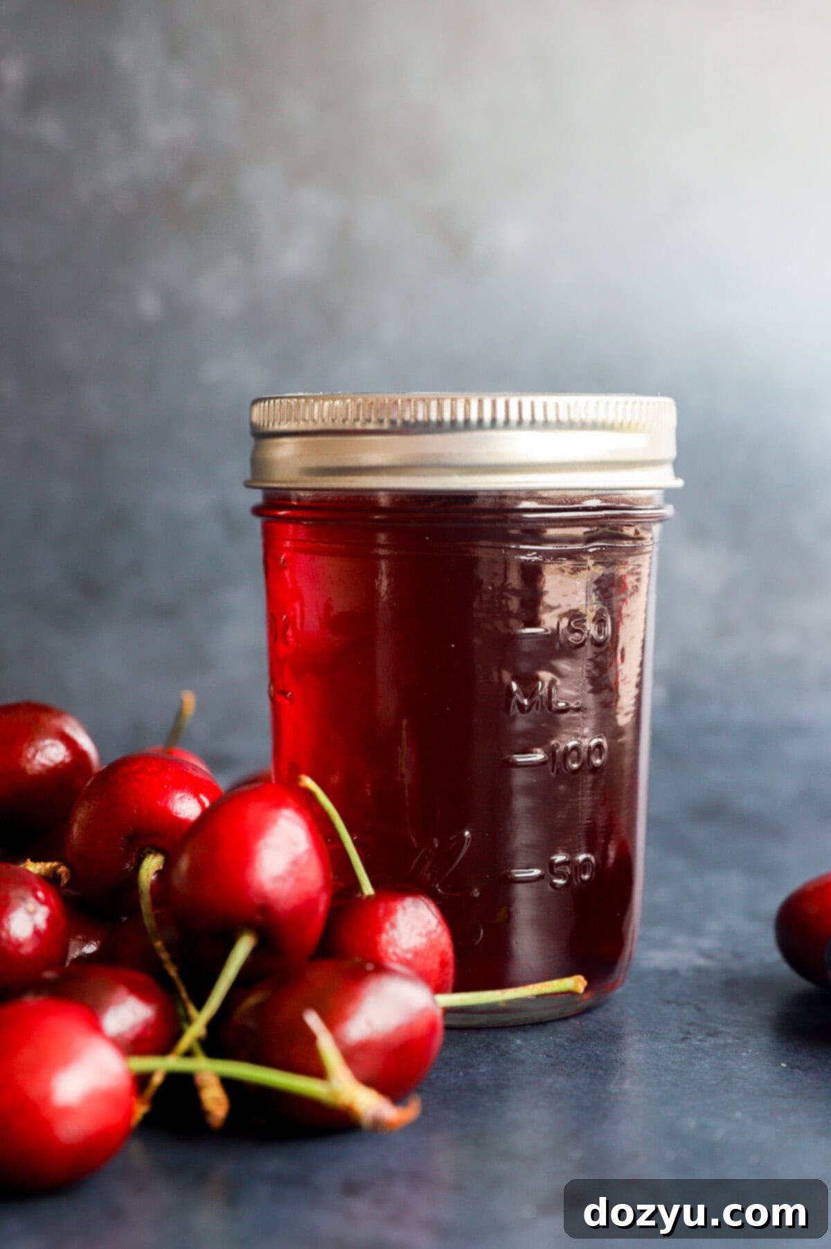 Sweet Cherry Elixir 7 flavored syrup in a jar with fresh cherries in a pile