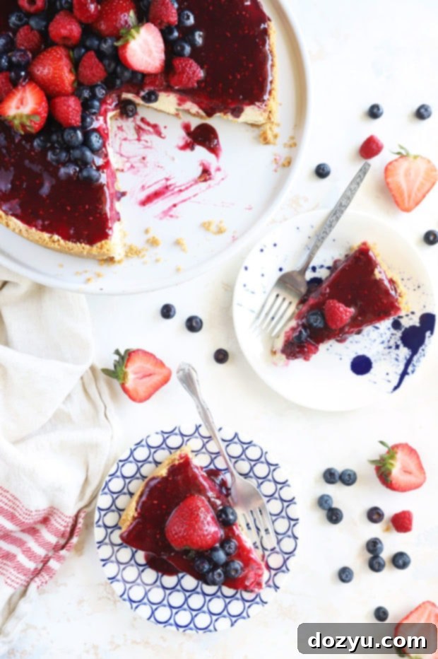 Berry Medley Cheesecake 3 Two slices of Triple Berry Cheesecake on a white plate, garnished with fresh berries.