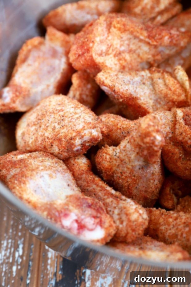 Sticky Bourbon Peach BBQ Wings 6 Chicken wings coated in dry rub in a mixing bowl, ready for grilling