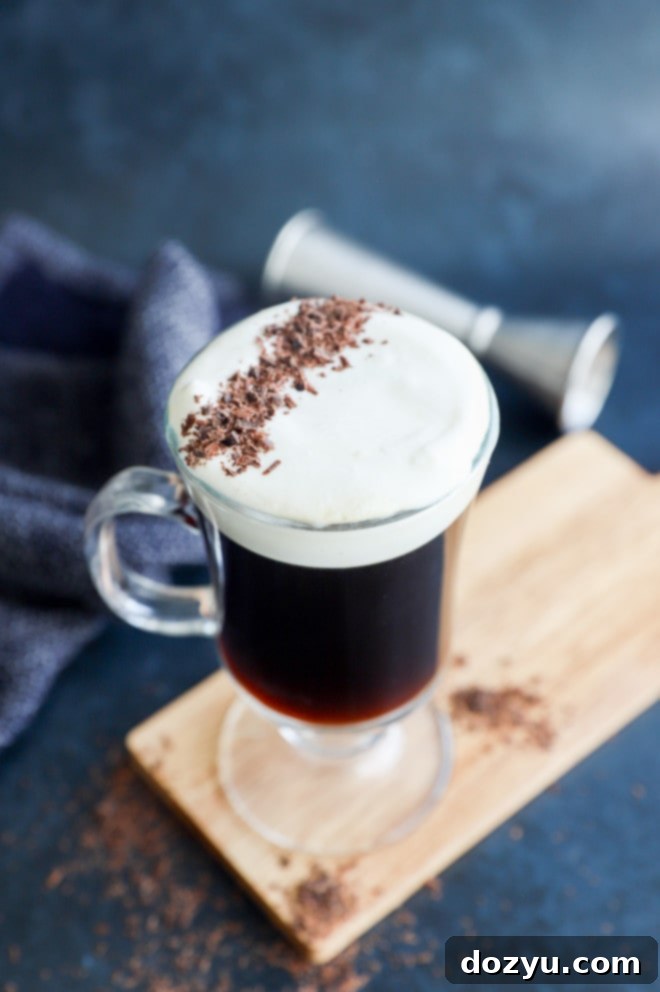 The Perfect Irish Coffee 7 Hot cocktail with whiskey on cutting board with jigger in the background