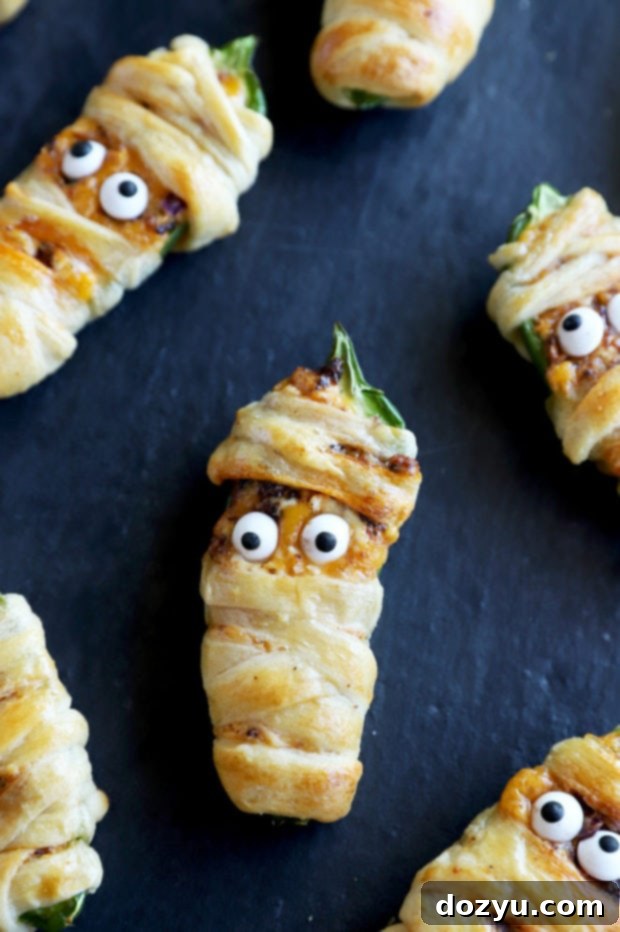 Spicy Chorizo Mummy Poppers 6 Jalapeno poppers for halloween on plate with green garnish