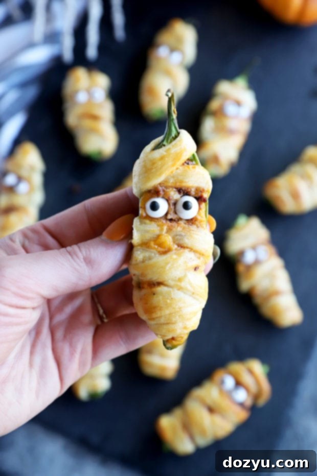 Spicy Chorizo Mummy Poppers 8 Hand holding jalapeno mummy popper image