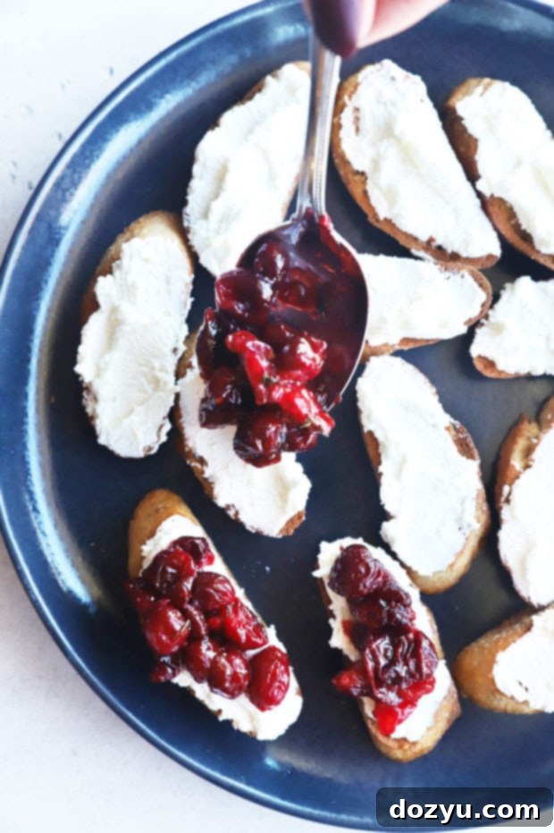 Sweet and Tangy Roasted Cranberry Goat Cheese Crostini 7 Adding cranberries to crostini image