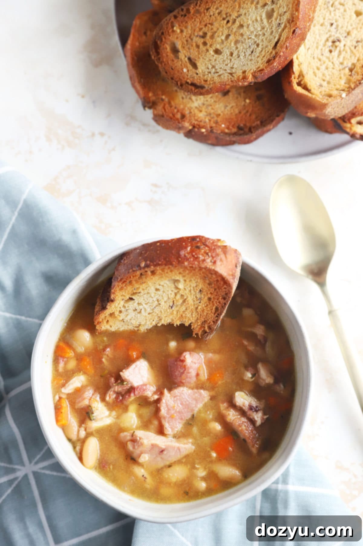 One Pot Ham and Bean Delight 4 An inviting overhead photo of Instant Pot Ham and Bean Soup in a bowl, served with slices of crusty bread.
