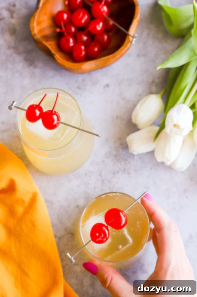 Sparkling Whiskey Sour 7 A hand gently holds a sparkling whiskey sour cocktail, garnished with a cherry and a lemon slice, against a soft, blurred background, evoking relaxation and enjoyment.