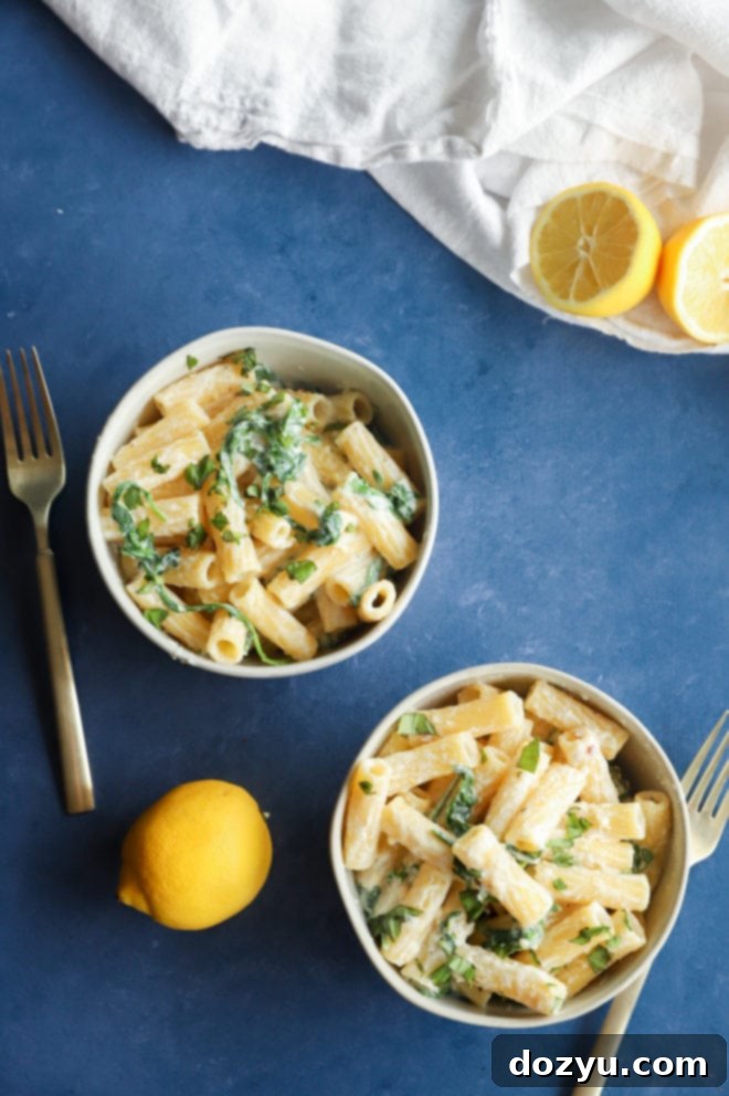 Lemony Cloud Pasta 3 Overhead photo of lemon ricotta pasta served in two bowls, garnished with lemon slices and arugula
