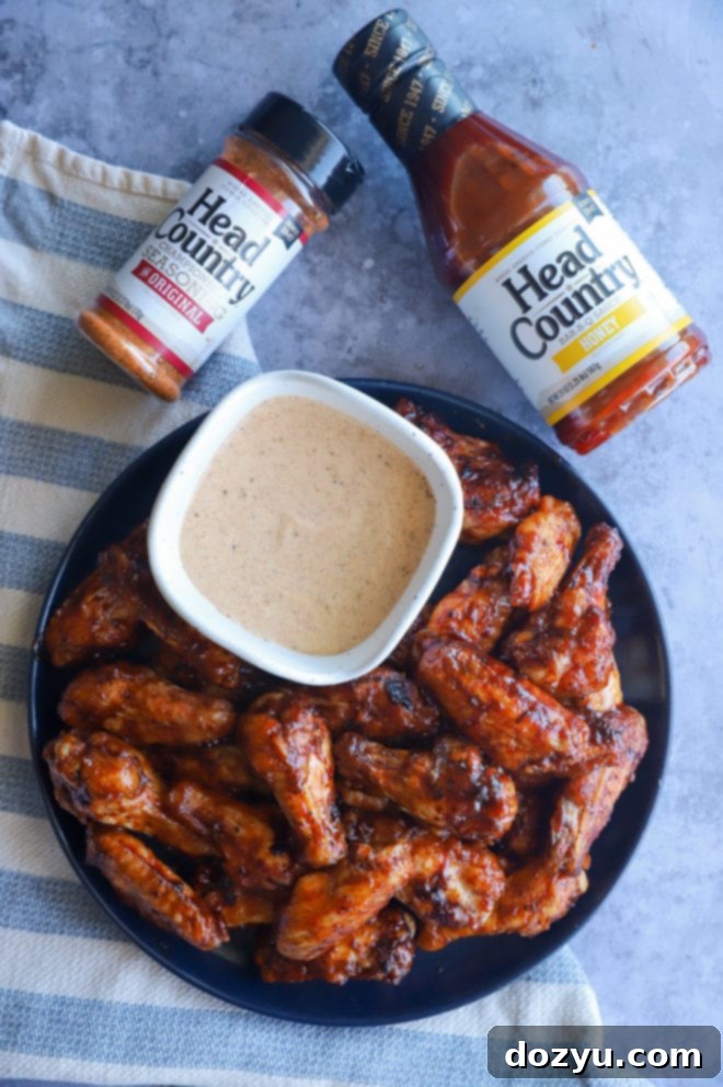 Glazed Honey BBQ Chicken Wings 4 Overhead image of a bowl filled with perfectly grilled wings, with a bottle of Head Country BBQ sauce prominently displayed, highlighting the main ingredient.