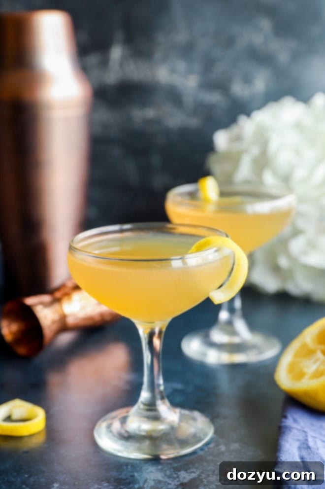 Two Bourbon Sidecar cocktails in elegant coupe glasses, garnished with lemon twists, on a dark surface.