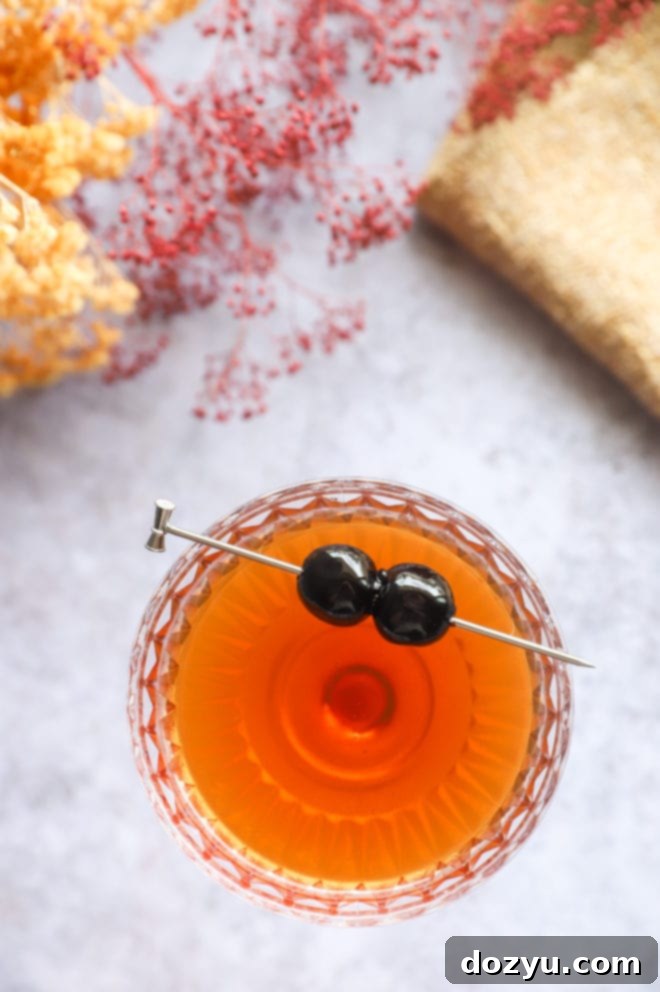 Bourbon Manhattan A Timeless Classic 6 Overhead image of a single coupe glass with a Manhattan cocktail and cherry garnish