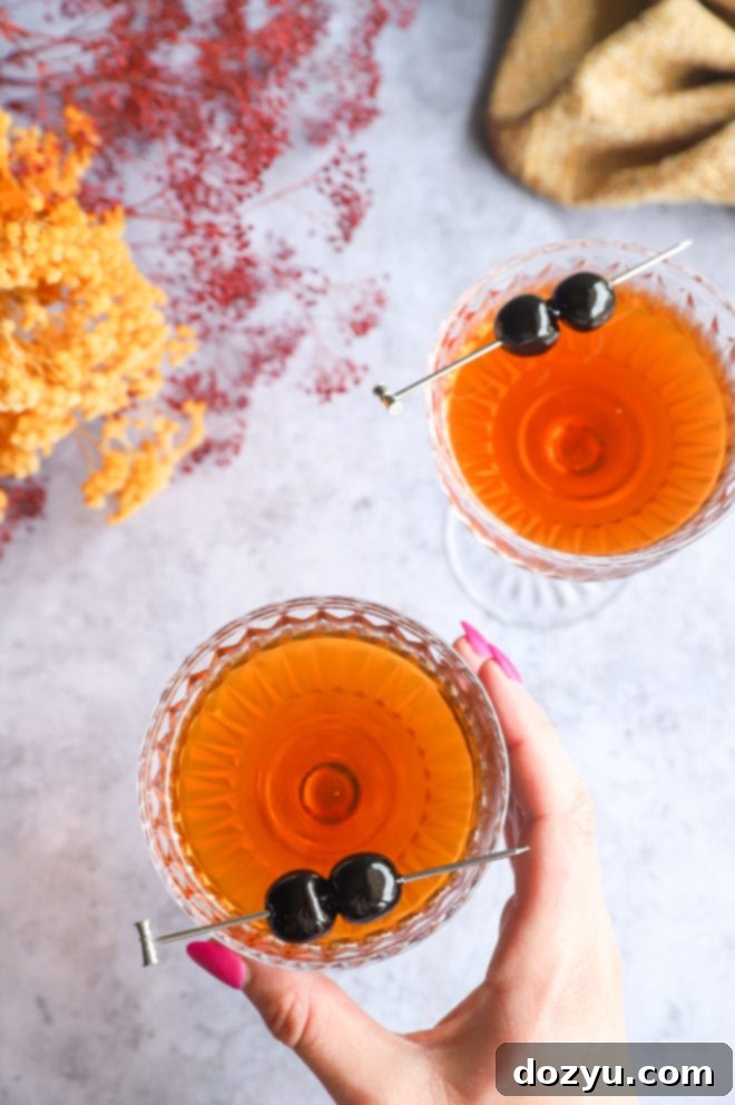 Bourbon Manhattan A Timeless Classic 7 Hand holding a coupe glass with a Bourbon Manhattan cocktail