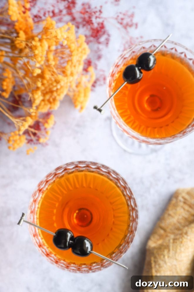 Bourbon Manhattan A Timeless Classic 3 Overhead image of two Bourbon Manhattans in coupe glasses, garnished with cherries