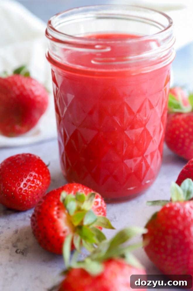 Strawberry coulis in a mason jar with strawberries