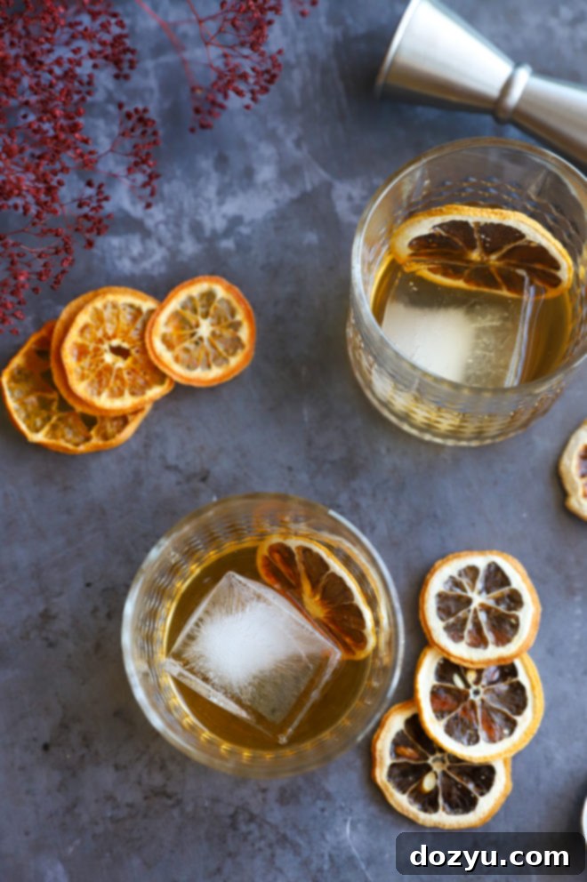 Smoldering Agave Classic 2 Overhead image of two Spicy Mezcal Old Fashioned cocktails in glasses, garnished with dried orange slices.