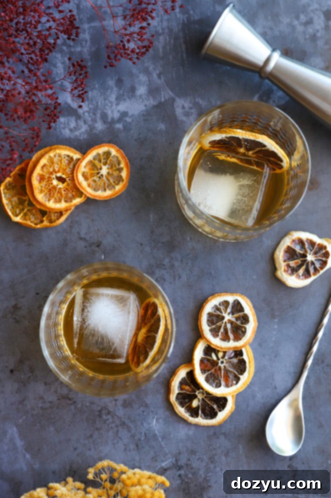 Smoldering Agave Classic 8 Image of two Spicy Mezcal Old Fashioned cocktails in glasses on a wooden surface.