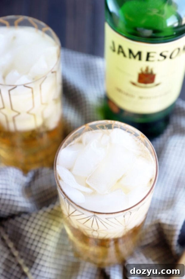 Two refreshing Jameson and Ginger cocktails, garnished with lime wedges, arranged invitingly on a dark surface.