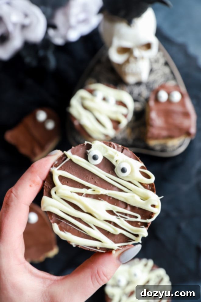 Ghoulishly Good Chocolate Peanut Butter Krispies 4 Hand holding mummy cereals treats, a creative Halloween dessert
