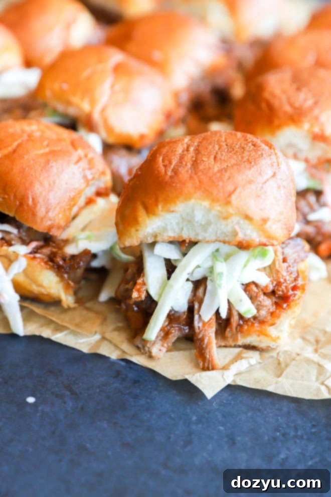 Tender BBQ Pulled Pork Sliders with Tangy Apple Coleslaw 11 Photo of sliders on parchment paper with coleslaw, ready to be picked up