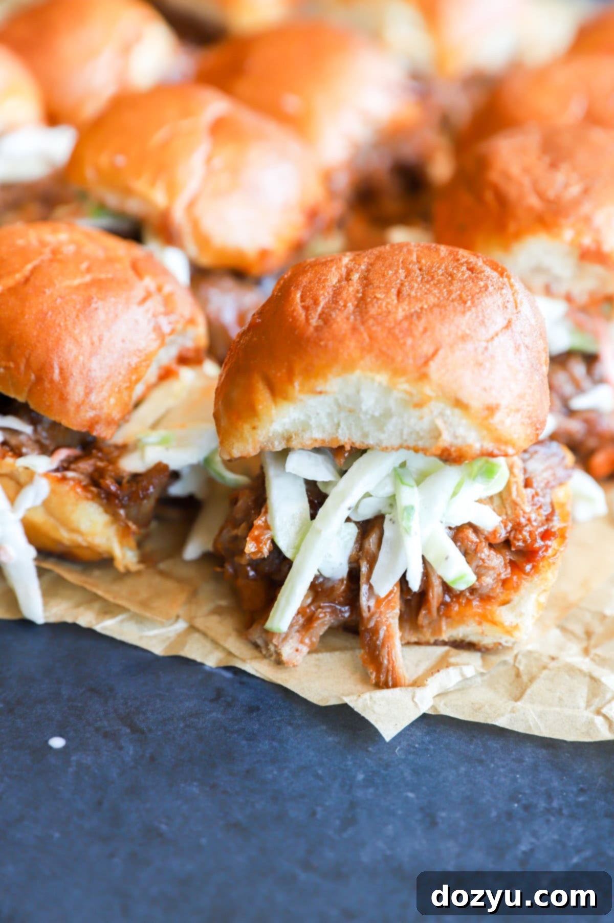 Tender BBQ Pulled Pork Sliders with Tangy Apple Coleslaw 12 Photo of sliders on parchment paper with coleslaw