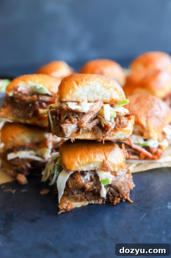 Tender BBQ Pulled Pork Sliders with Tangy Apple Coleslaw 3 Side image of pork sandwiches stacked, showing the layers of pulled pork and coleslaw