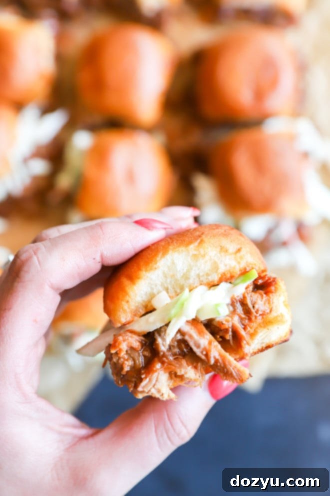 Tender BBQ Pulled Pork Sliders with Tangy Apple Coleslaw 4 Hand holding sandwich with coleslaw picture, showing the crispy texture of the coleslaw