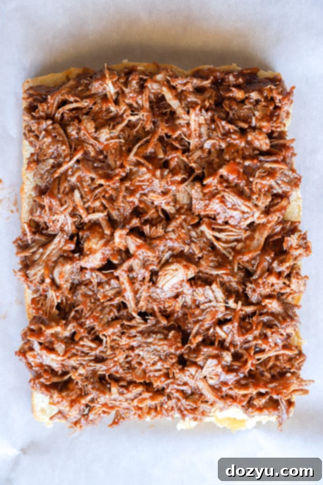 Tender BBQ Pulled Pork Sliders with Tangy Apple Coleslaw 7 Pulled pork on buns on baking sheet image, showing the assembly process
