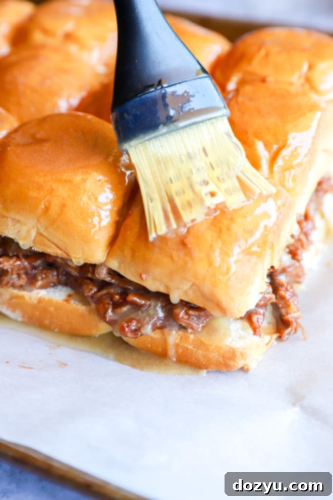 Tender BBQ Pulled Pork Sliders with Tangy Apple Coleslaw 9 Brushing pulled pork sliders with butter image, showing the final preparation step