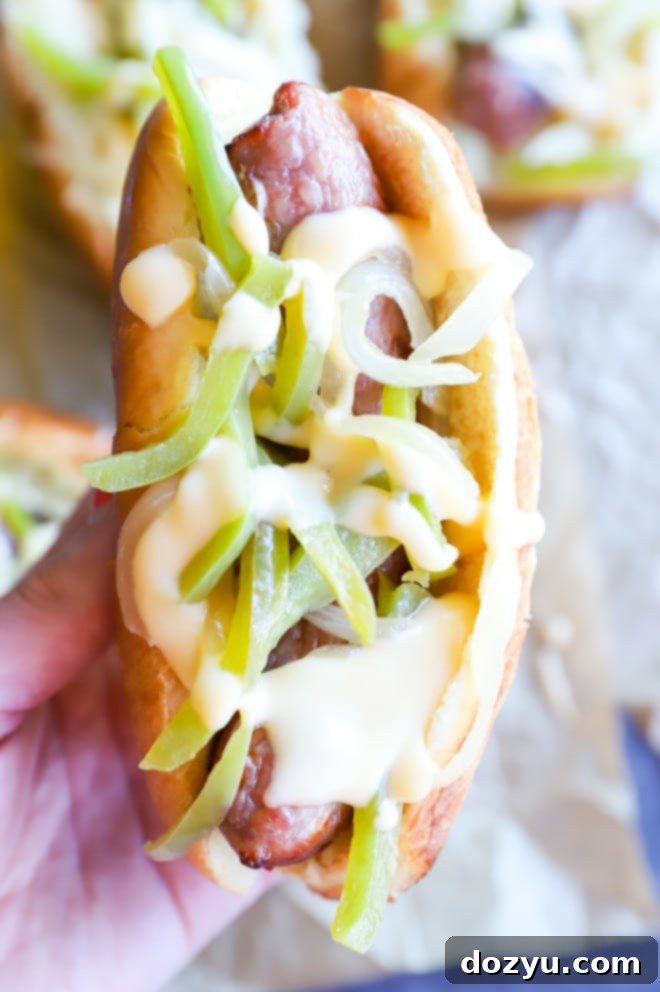 Philly Cheesesteak Beer Brats 4 Close-up of a hand holding a grilled bratwurst, perfectly cooked and ready for toppings.