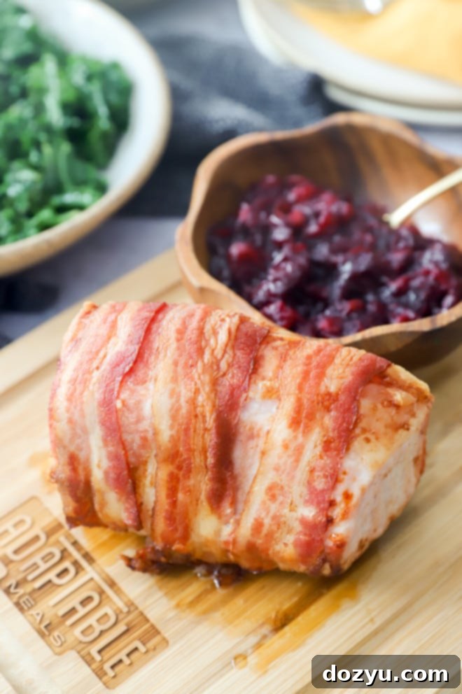 Crispy Air Fryer Bacon Wrapped Pork Loin 3 Pork and roasted cranberries on cutting board image