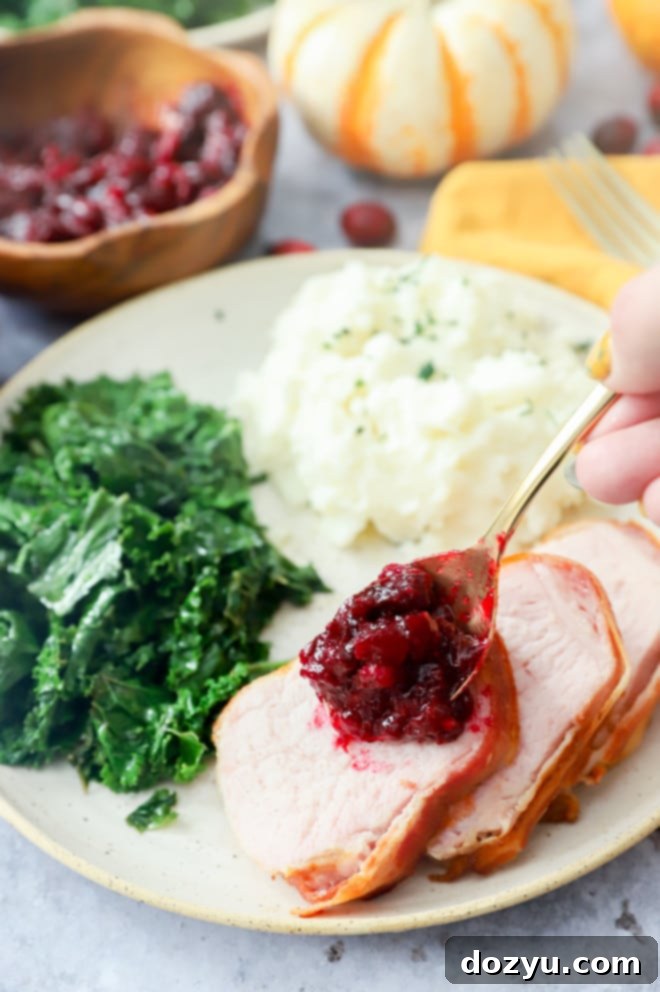 Crispy Air Fryer Bacon Wrapped Pork Loin 9 spooning cranberries onto bacon wrapped pork tenderloin
