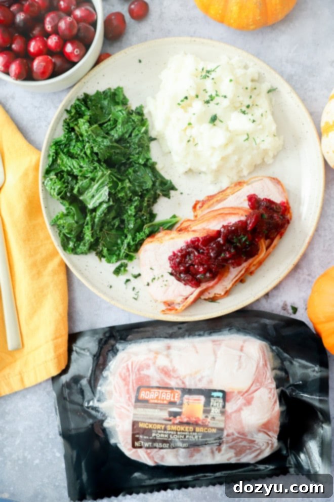 Crispy Air Fryer Bacon Wrapped Pork Loin 10 Image of pork with potatoes and kale and cranberries
