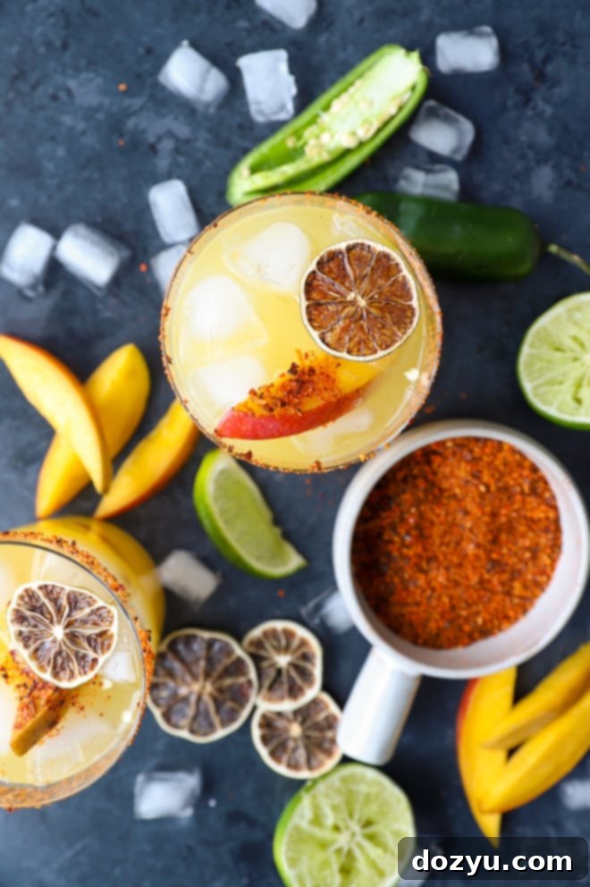 Spicy Mango Margarita Overhead view of two spicy mango margaritas, brightly colored with fresh garnishes.