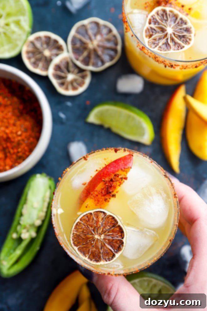 Spicy Mango Margarita A hand holding a spicy mango margarita, showing the texture and garnish clearly.