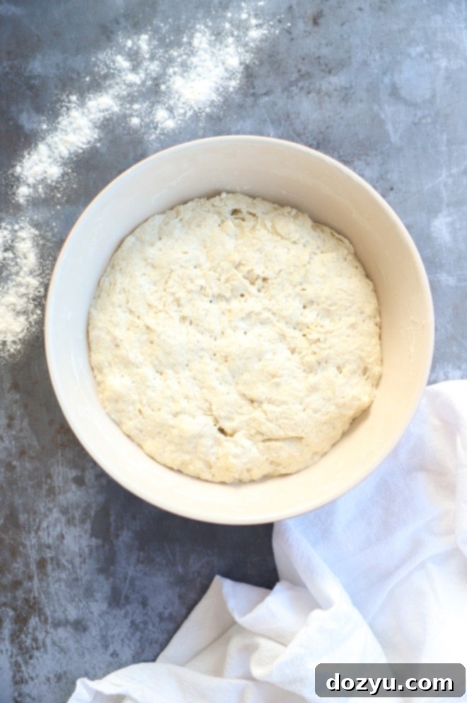 Effortless Overnight No Knead Bread 4 Dough rising in a bowl with flour and linen