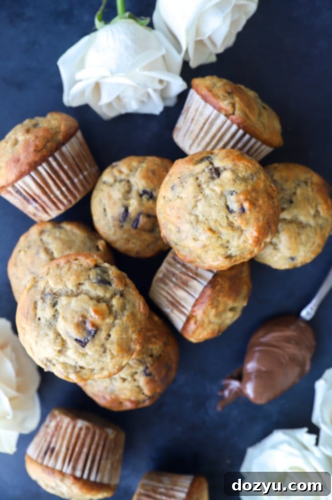 Decadent One-Bowl Banana Nutella Muffins 3 A delectable pile of banana muffins with visible chocolate chips, freshly baked and ready to be enjoyed.