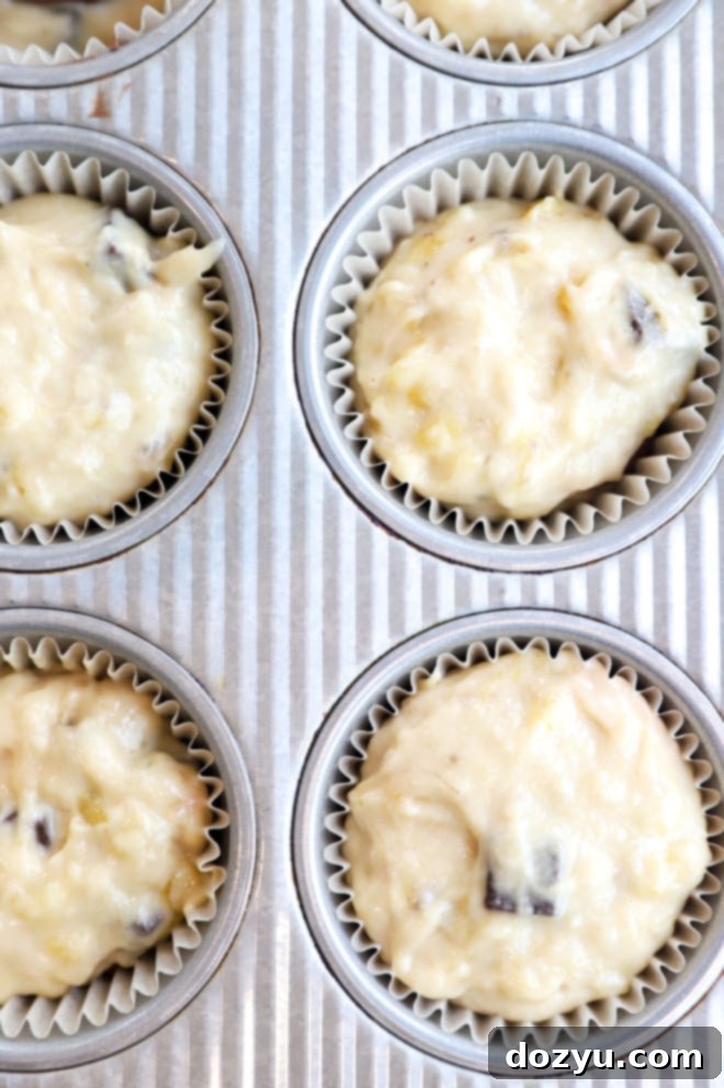Decadent One-Bowl Banana Nutella Muffins 6 Muffins in the pan before baking, with visible Nutella peeking through