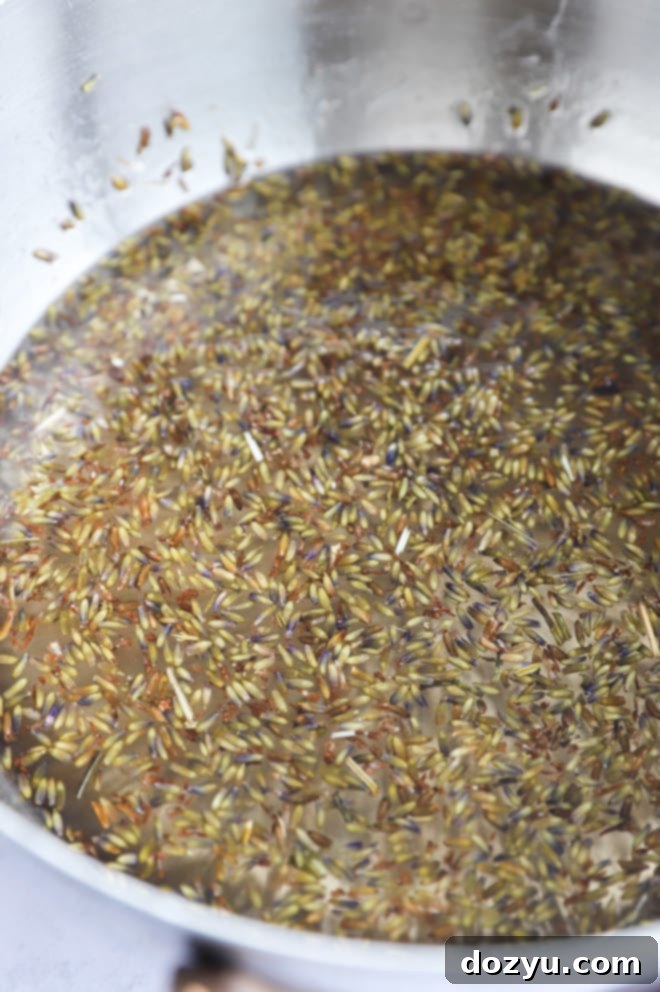Fragrant Lavender Syrup 4 A close-up of lavender simple syrup gently simmering in a saucepan on the stove, with lavender buds visibly infusing the liquid.