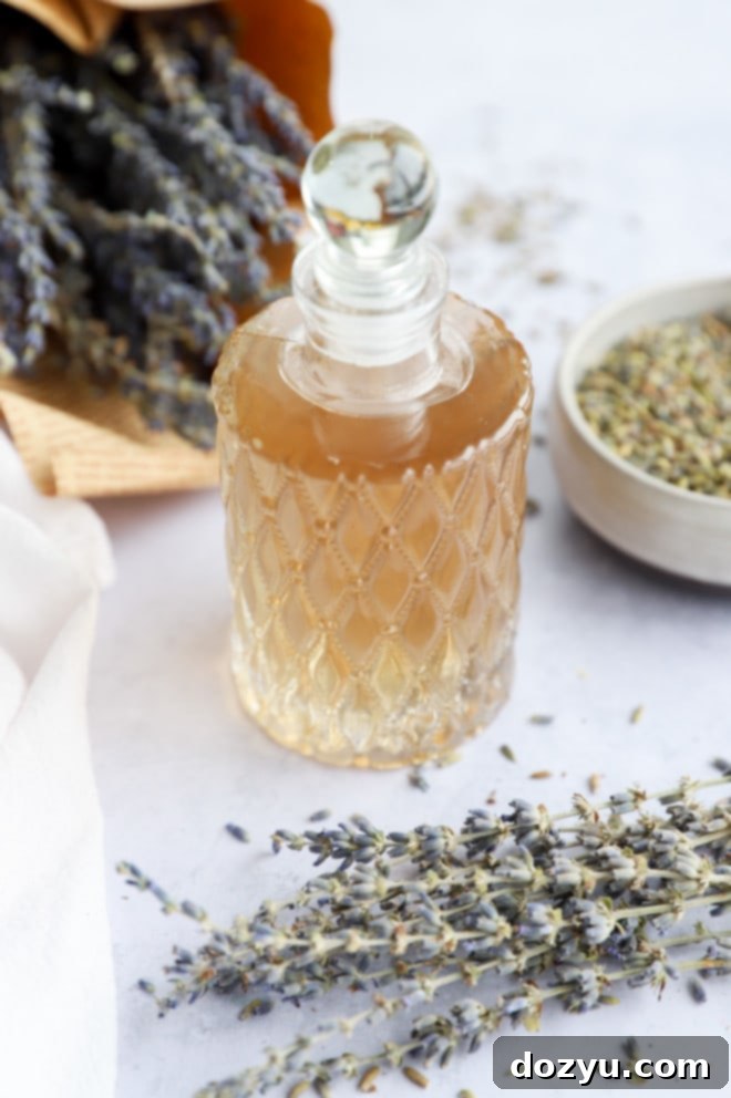 Fragrant Lavender Syrup 5 A charming glass bottle filled with clear lavender simple syrup, adorned with a label, sitting beside fresh lavender sprigs.