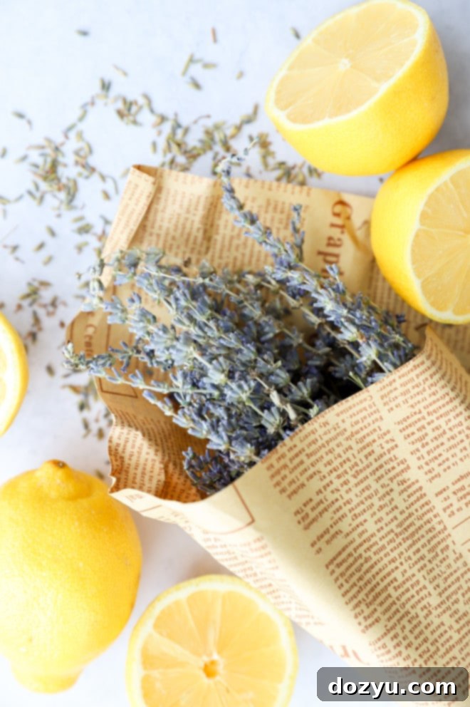 Blissful Lavender Lemonade Cocktail 6 Overhead flat lay of fresh lemons, dried lavender, and small white flowers on a light wooden background, illustrating natural cocktail ingredients.