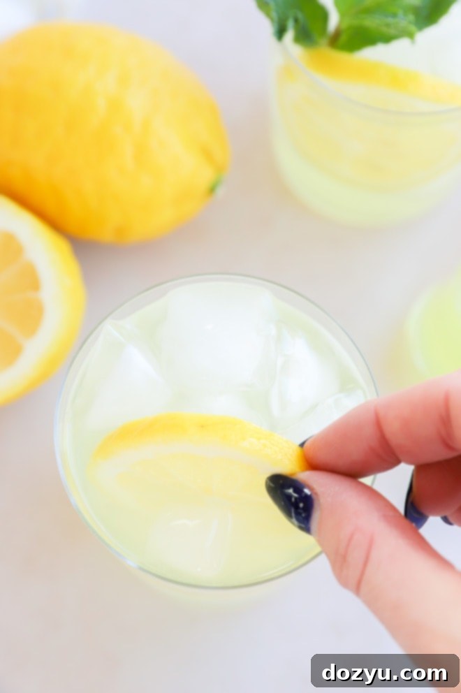 Limoncello Spritz 5 Close-up of a hand garnishing a lemon cocktail with a lemon slice and mint