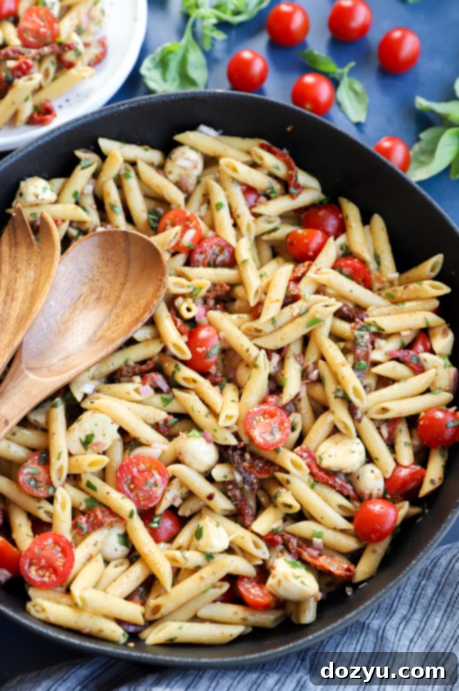 Sun-Kissed Pasta Salad 8 Overhead image of pasta in a bowl with serving spoons image