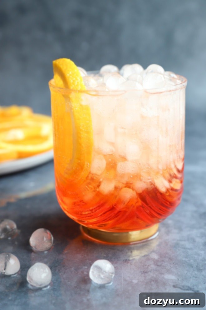 Aperol Fizz 9 A refreshing Aperol Soda cocktail in a glass, surrounded by ice, captured up close to highlight its inviting color.