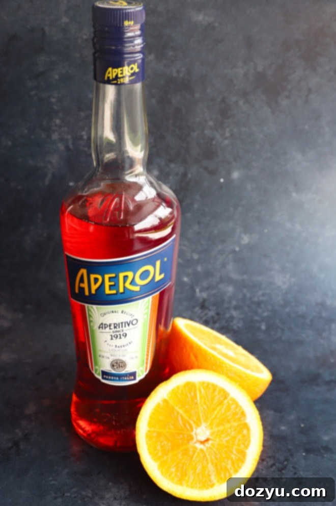 Aperol Fizz 3 Bottle of Aperol next to a fresh orange cut in half, illustrating the key ingredient of Aperol Soda.