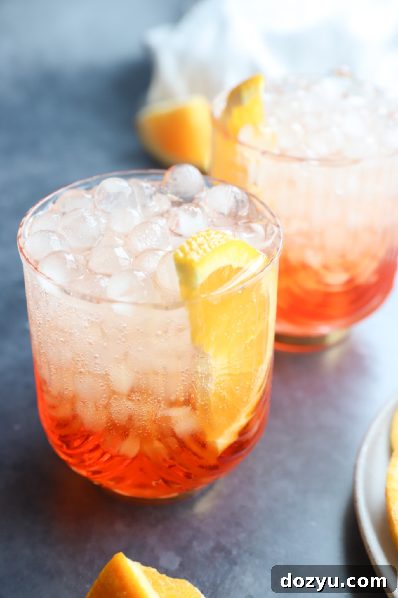Aperol Fizz 7 Two Aperol soda cocktails in glasses with unique round ice cubes and orange slices, a refreshing Italian drink.